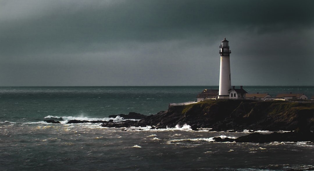 Old stone coastal lighthouse against a stormy dusk sky